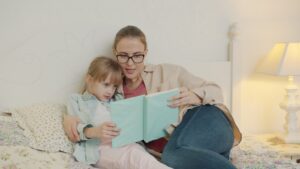 Woman reading a book to a young girl.